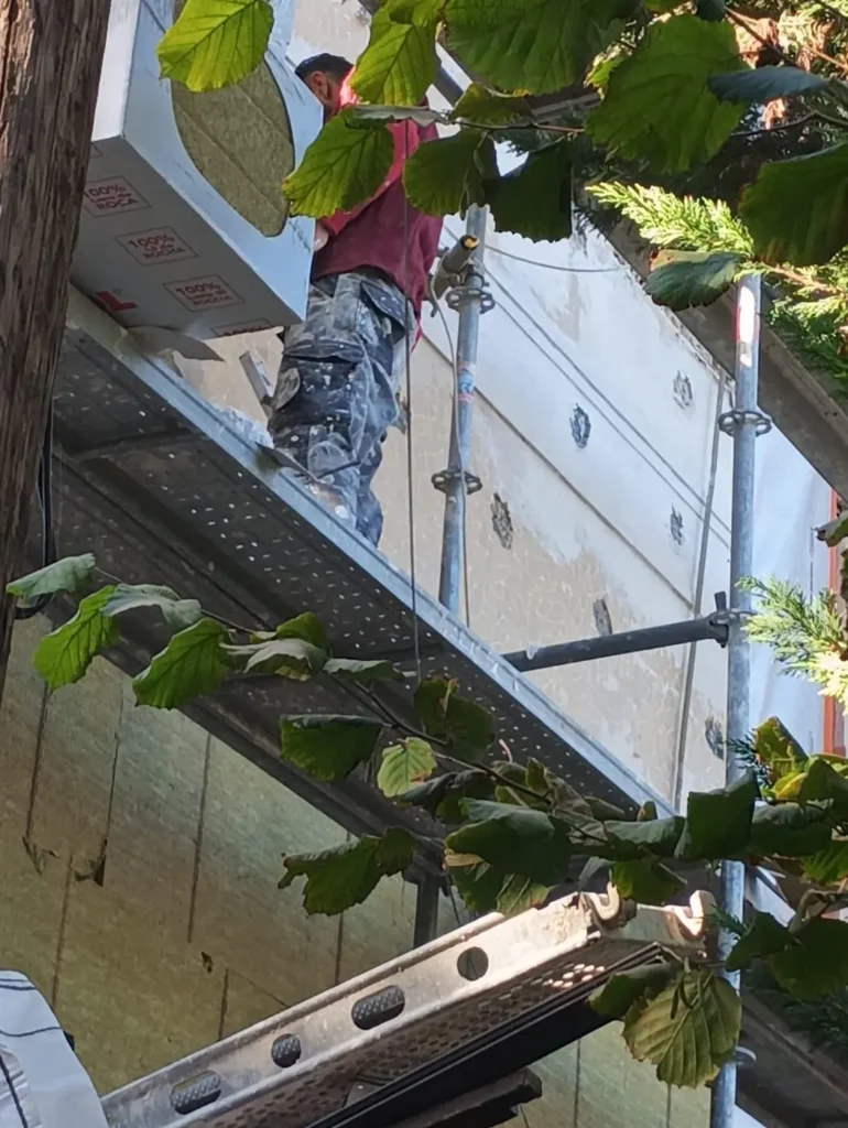Ouvrier sur échafaudage, rénovation extérieure.